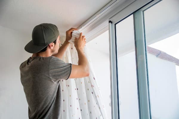 Hombre instalando cortinas por su cuenta