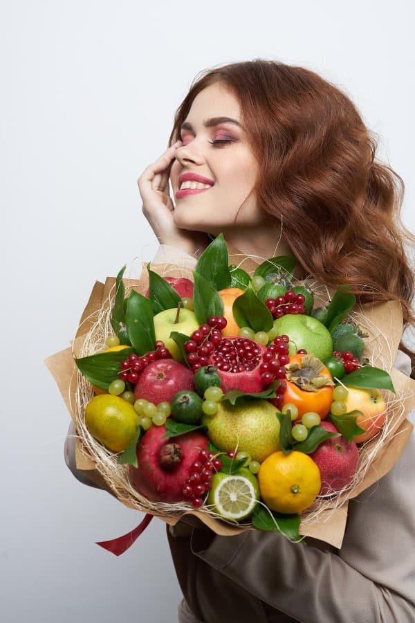 Mujer sosteniendo un ramillete de frutas decorativo