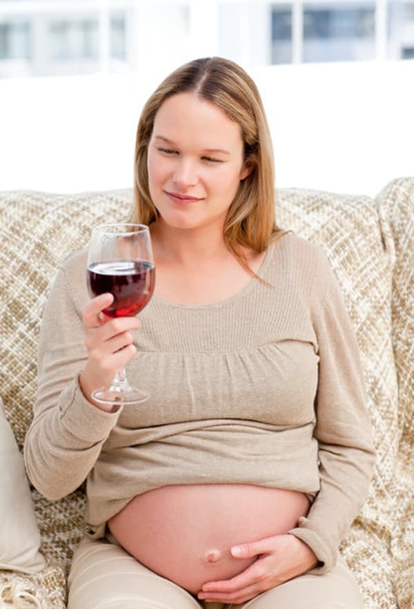 Embarazada mirando una copa de vino