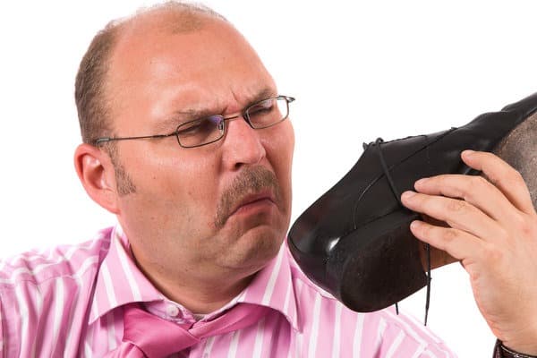 Hombre oliendo zapatos con mal olor
